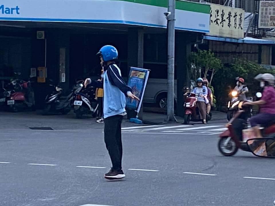 男學生頭戴安全帽，站在路口中央指揮車輛通行。（翻攝自花蓮同鄉會）