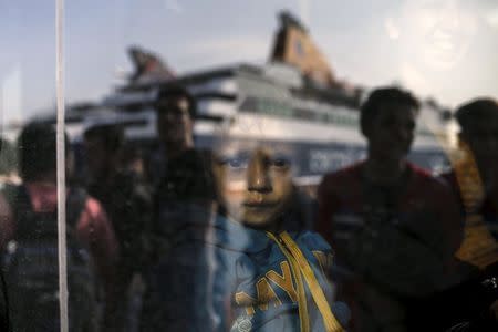 A migrant boy is seen through a bus window as refugees and migrants arrive aboard the passenger ferry Blue Star Patmos from the island of Lesbos at the port of Piraeus, near Athens, Greece, October 19, 2015. REUTERS/Alkis Konstantinidis