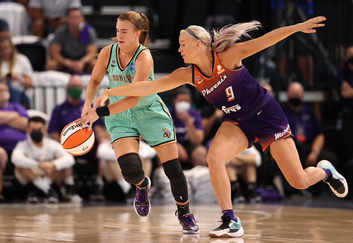 New York's Sabrina Ionescu controls the ball under pressure from Phoenix's Sophie Cunningham during the first half of their first-round WNBA playoff game at Grand Canyon University Arena in Phoenix on Sept. 23, 2021. (Christian Petersen/Getty Images)