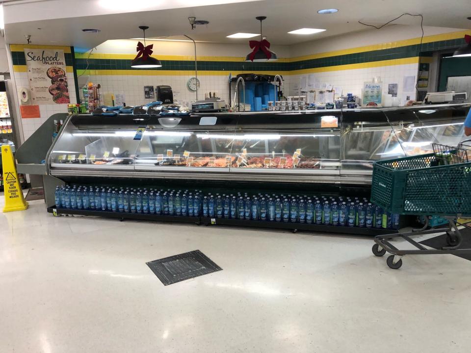 A seafood counter at Sack N Save in Hilo, Hawaii, including multiple types of poke and bottled beverages under the counter