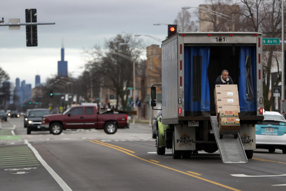 A delivery man unloads his truck on what is usually a busy Madison Ave. in the Village of Oak Park, Ill., Friday, March 20, 2020. There are at least three confirmed cases of COVID-19 in Oak Park, just nine miles from downtown Chicago, where the mayor has ordered residents to shelter in place. With so few tests available, surely there are others, says Tom Powers, spokesman for the village of about 52,000 in a metropolitan area with millions. (AP Photo/Charles Rex Arbogast)