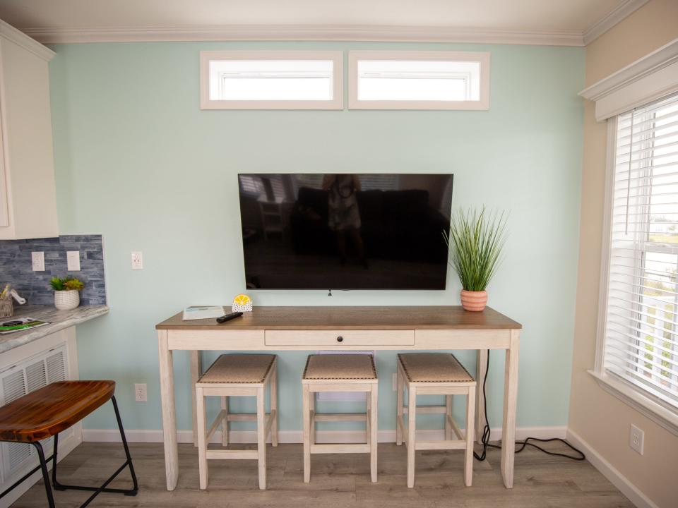 A TV hung on the wall above a table with three chairs.