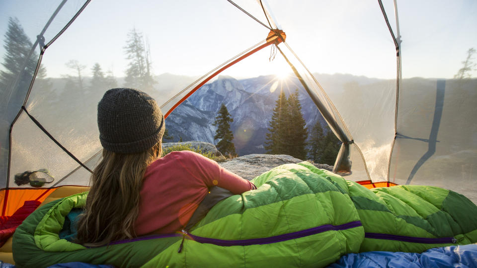 A woman watching sunrise from a tent