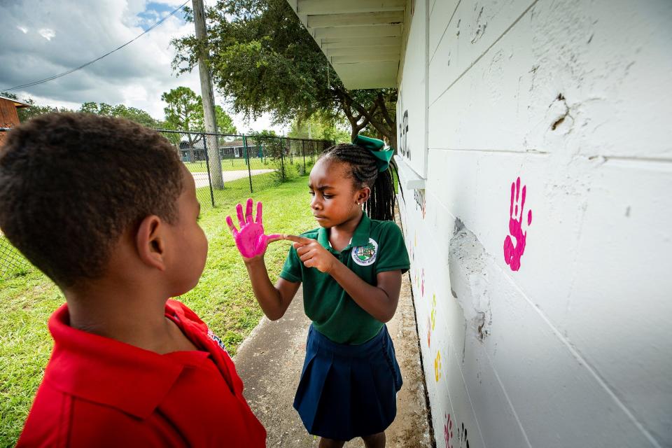 Aubrey Amos, 6, inspects the paint on her hand Tuesday afternoon as he cousin, Paxton Amos, looks on. The kids are part of Ambitious Young Believers, founded by Paxton's father, Lee Amos, a Mulberry native.