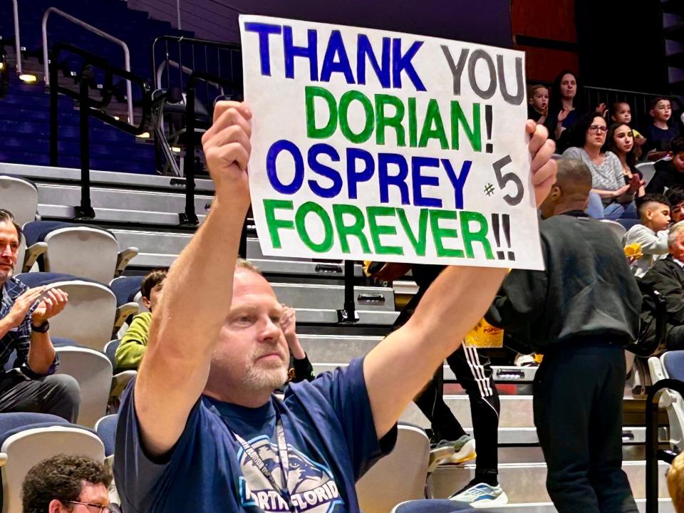 Tim O'Leary, a member of the University of North Florida Physical Therapy staff, holds up a sign acknowledging Osprey senior Dorian James before Senior Night on Friday against Stetson.