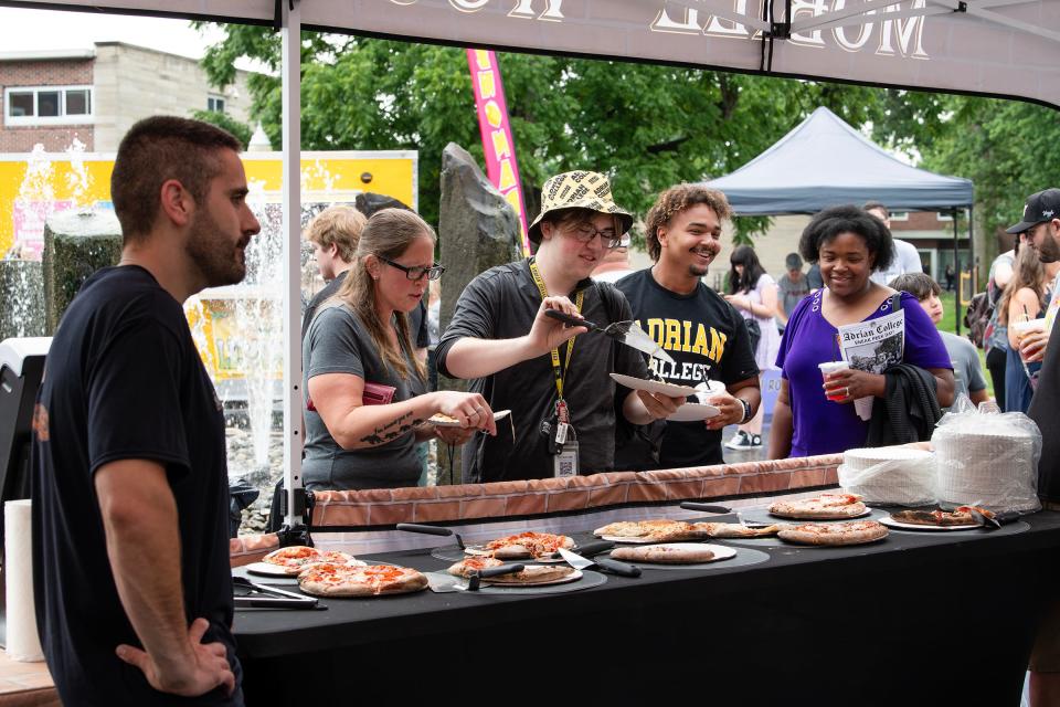 Owen Callahan, third from left, and his mother Jen Barringer, second from left, stop at one of the several food trucks on Adrian College's campus Friday, July 12, 2024, for free pizza as part of AC's "Sneak Peek Day" for incoming students and families.