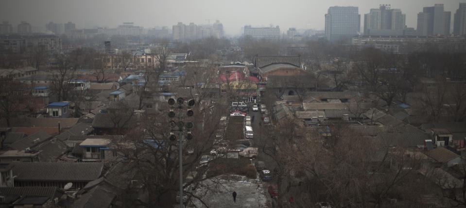 In this Jan. 15, 2013 photo, a resident, bottom, walks in a "hutong" neighborhood behind the Drum Tower and the Bell Tower in central Beijing, China. The district government wants to demolish these dwellings, move their occupants to bigger apartments farther from the city center and redevelop a square in 18th century Qing Dynasty fashion. (AP Photo/Alexander F. Yuan)