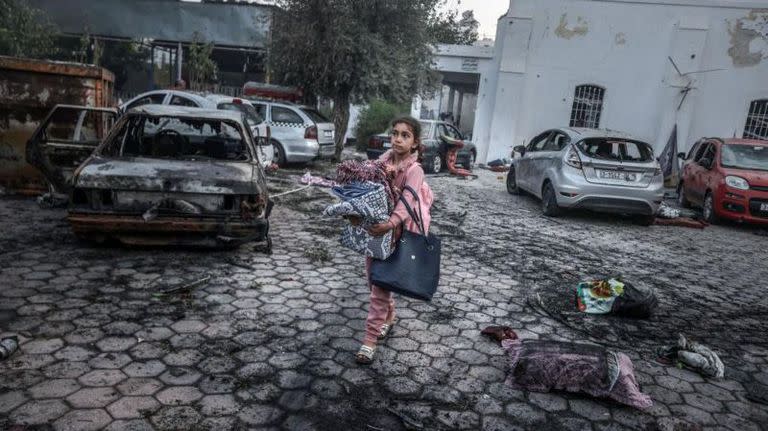 Una niña recolecta pertenencias cerca del hospital que fue atacado ayer en Gaza, en donde hubo cientos de muertos según las autoridades de la franja