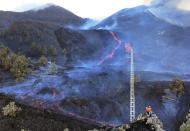 Scientists with the Canary Islands' volcanology institute, Involcan, inspect as the lava flows from a volcano on the Canary island of La Palma, Spain, Saturday, Oct. 30, 2021. Scientists from around the world flocking to an eastern Atlantic Ocean island are using an array of new technologies available to them in 2021 to scrutinize — from land, sea, air, and even space — a rare volcanic eruption. But despite technological and scientific leaps, predicting volcanic eruptions and, more crucially, how they end, remains a mystery. (AP Photo/Emilio Morenatti)