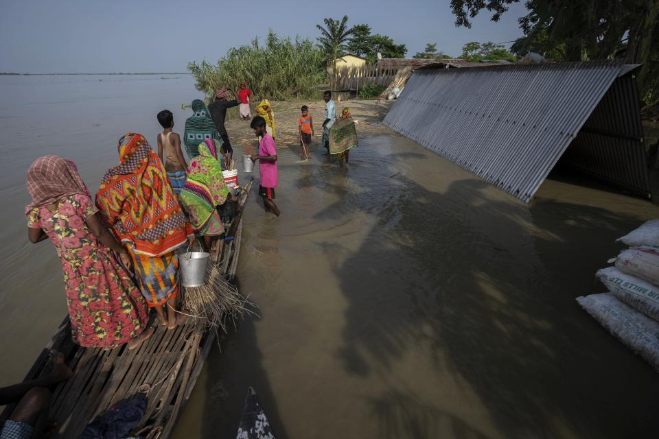 Villagers reach higher ground after they left their submerged house in Sandahkhaiti, a floating island village in the Brahmaputra River in Morigaon district, Assam, India, Tuesday, Aug. 29, 2023. (AP Photo/Anupam Nath)