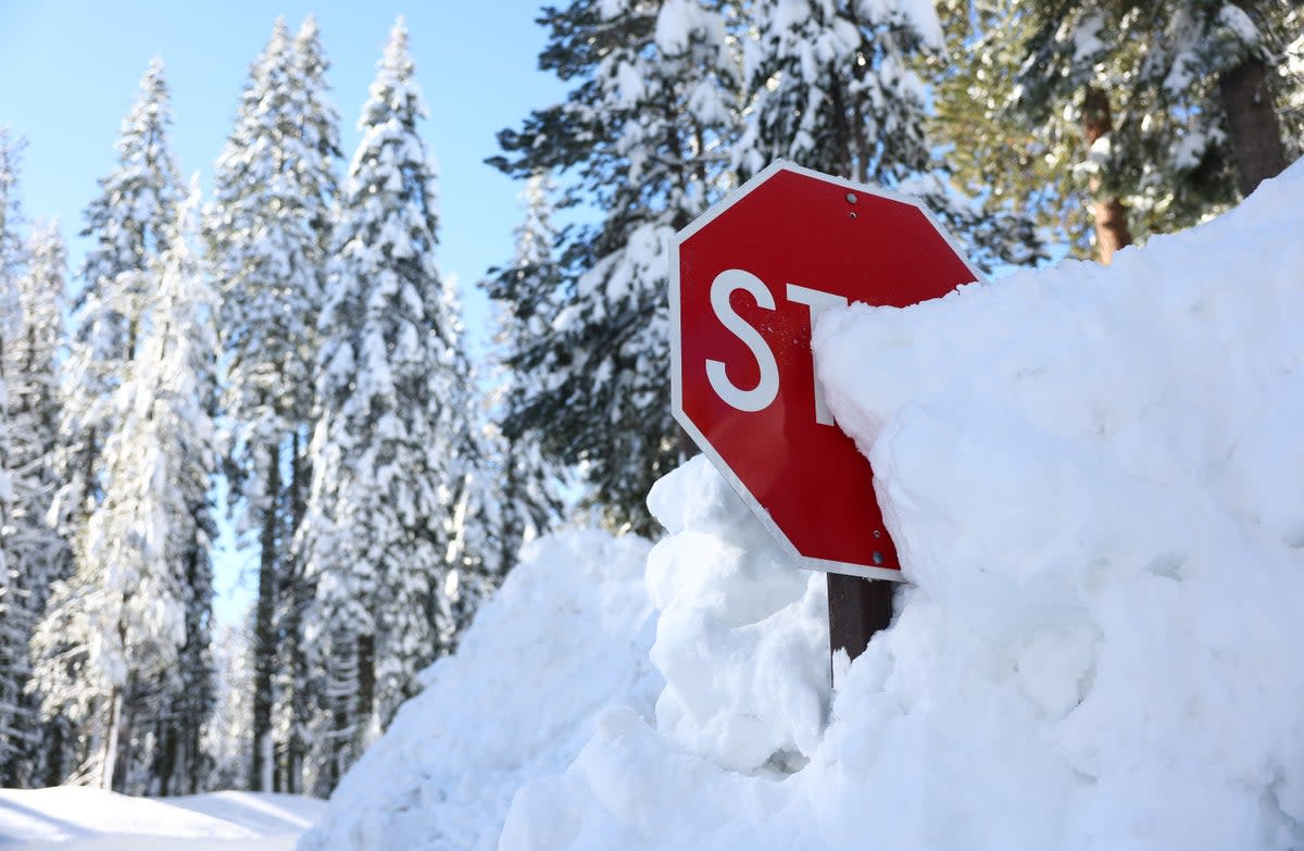 A stop sign is partially buried in a snowbank after a series of atmospheric river storms on January 20, 2023 in Yosemite National Park, California (Getty Images)