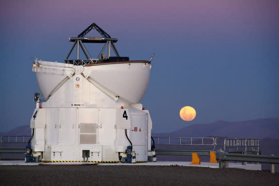 In Chile's Atacama Desert, home of the Paranal Observatory, the moon rises reddishly with one of the four Auxiliary Telescopes standing in the foreground.