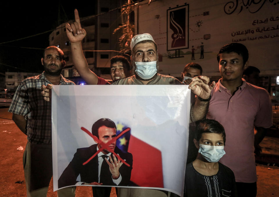 GAZA, PALESTINE - 2020/10/25: Protester holding a placard with a crossed out image of the French president during the demonstration. Palestinians in the city of Rafah protest against the publishing of cartoons as Prophet Muhammad in a French newspaper and the statement of French President Emmanuel Macron. (Photo by Yousef Masoud/SOPA Images/LightRocket via Getty Images)