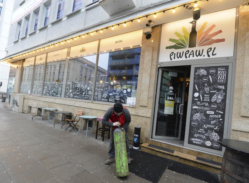 A man delivers a supply of heating gas to Warsaw's popular Piw Paw pub in Warsaw, Poland, Monday, Jan. 25, 2021, a business that is struggling to survive under lockdown by organizing legal, small-scale educative meetings and courses for beer lovers. (AP Photo/Czarek Sokolowski)