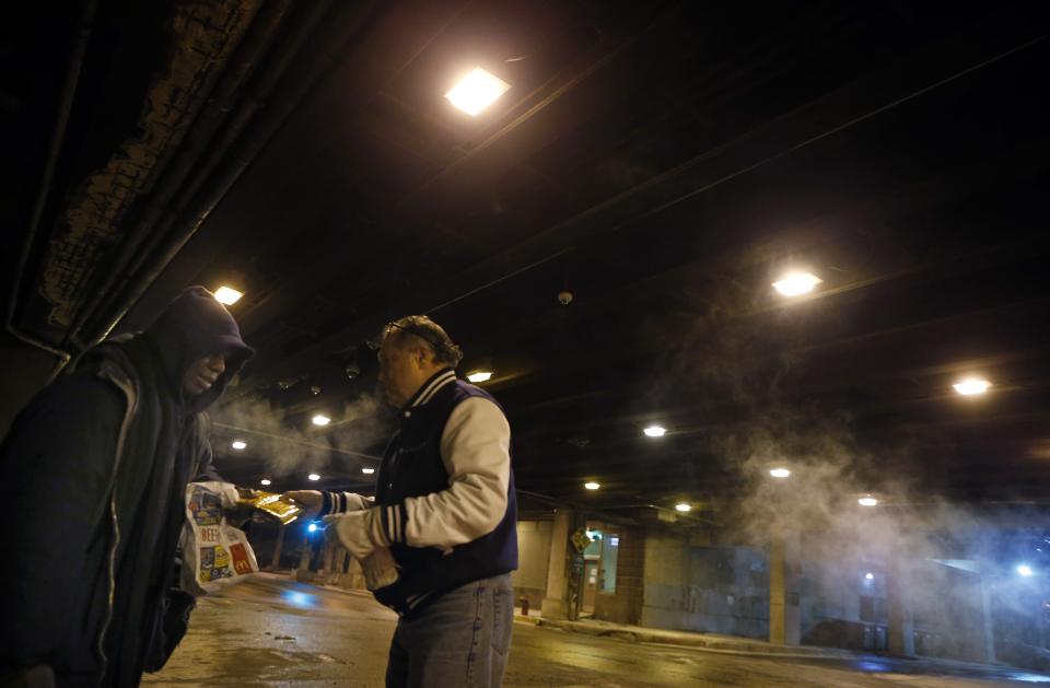 Doctor Angelo gives some packs of hand warmers to a homeless man under the overpasses on Lower Wacker Drive in Chicago