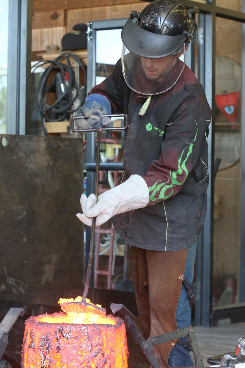 Dan Minosky scrapes impurities off the top a crucible of molten bronze.