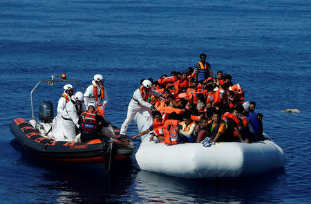 Rescuers from Malta-based NGO Migrant Offshore Aid Station (MOAS) distribute life jackets to migrants on a rubber dinghy in central Mediterranean on international waters off Zuwarah, Libya, April 14, 2017. REUTERS/Darrin Zammit Lupi