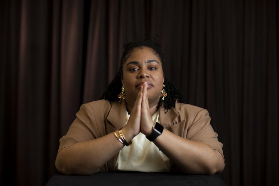 a woman with her elbows on a table and her palms together