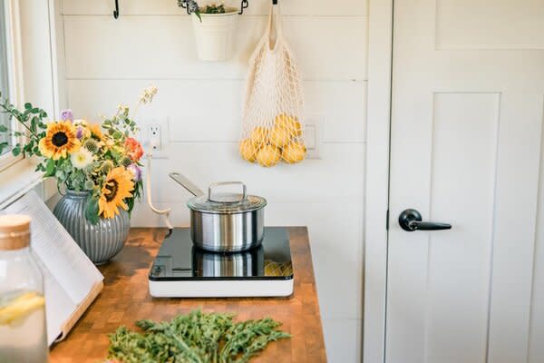 The kitchen features a TILLREDA portable induction cooktop that can be easily stored away when not in use. The solid wood and veneer SKOGSÅ countertop is made with the whole tree—including the branches and twigs—for minimal waste.