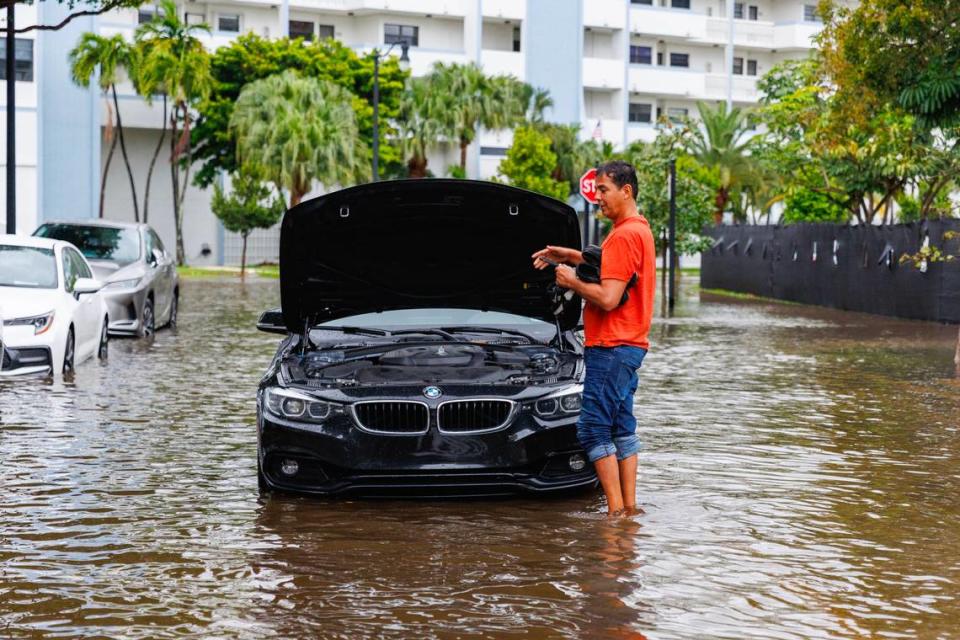 Una persona se encuentra junto a su vehículo varado en la carretera inundada debido a las fuertes lluvias en North Bay Rd y 179th Dr. en Sunny Isles Beach el miércoles 12 de abril de 2023.