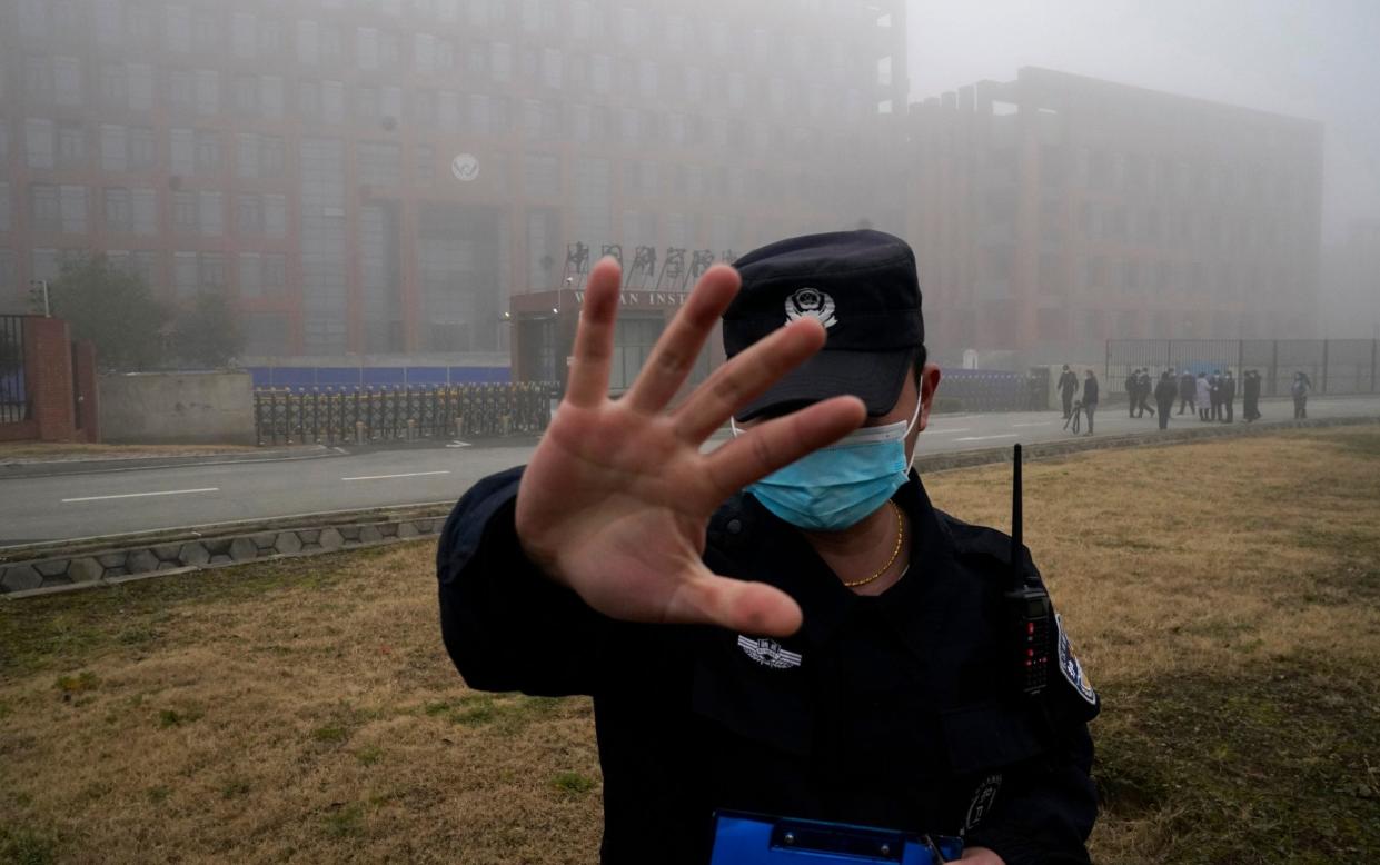 A security person moves journalists away from the Wuhan Institute of Virology after a World Health Organization team arrived for a field visit in Wuhan in China's Hubei province on Feb. 3, 2021 - Ng Han Guan/AP Photo