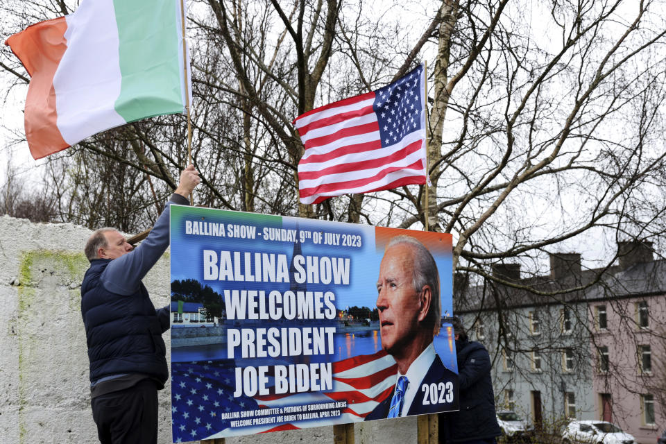 Ray Clarke, left, and Eddie Ruane put up flags in Ballina, Ireland, Tuesday, April, 4, 2023. Excitement is building in Ballina, a small Irish town that was home to some of President Joe Biden's ancestors. Biden is scheduled to visit the town next week, part of a four-day trip to Ireland and neighboring Northern Ireland. (AP Photo/Peter Morrison)
