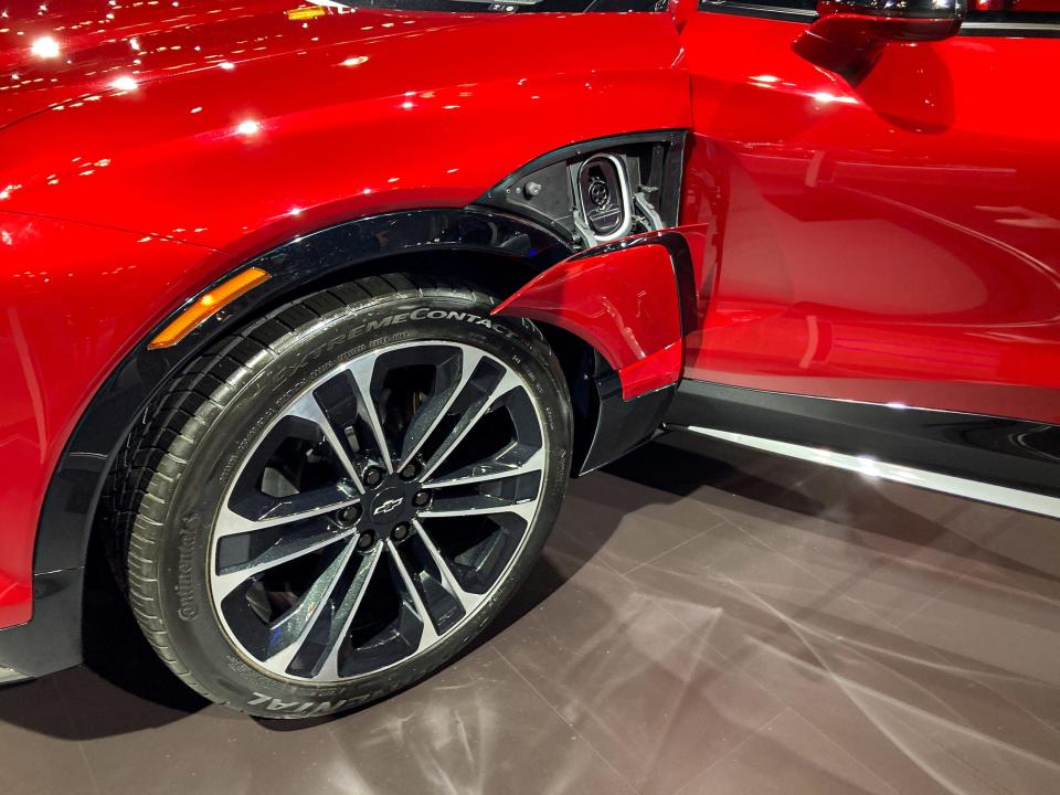 A close-up photo of the front wheel and charging port of a red Chevrolet Blazer EV.