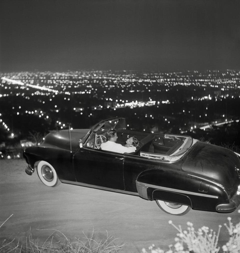 A couple in a convertible overlooking L.A. at night in a historical photo