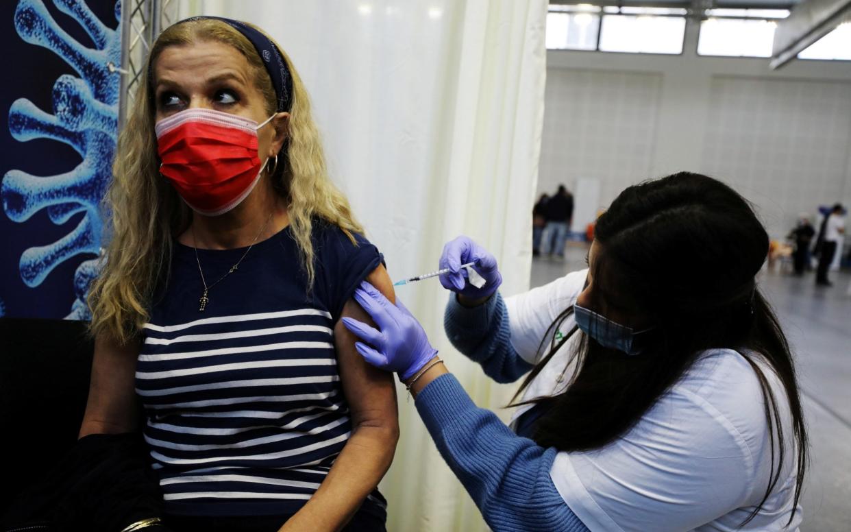 A woman receives a vaccination against the coronavirus disease (COVID-19) at a temporary Clalit healthcare maintenance organisation (HMO) centre, at a basketball court in Petah Tikva - Reuters/Reuters