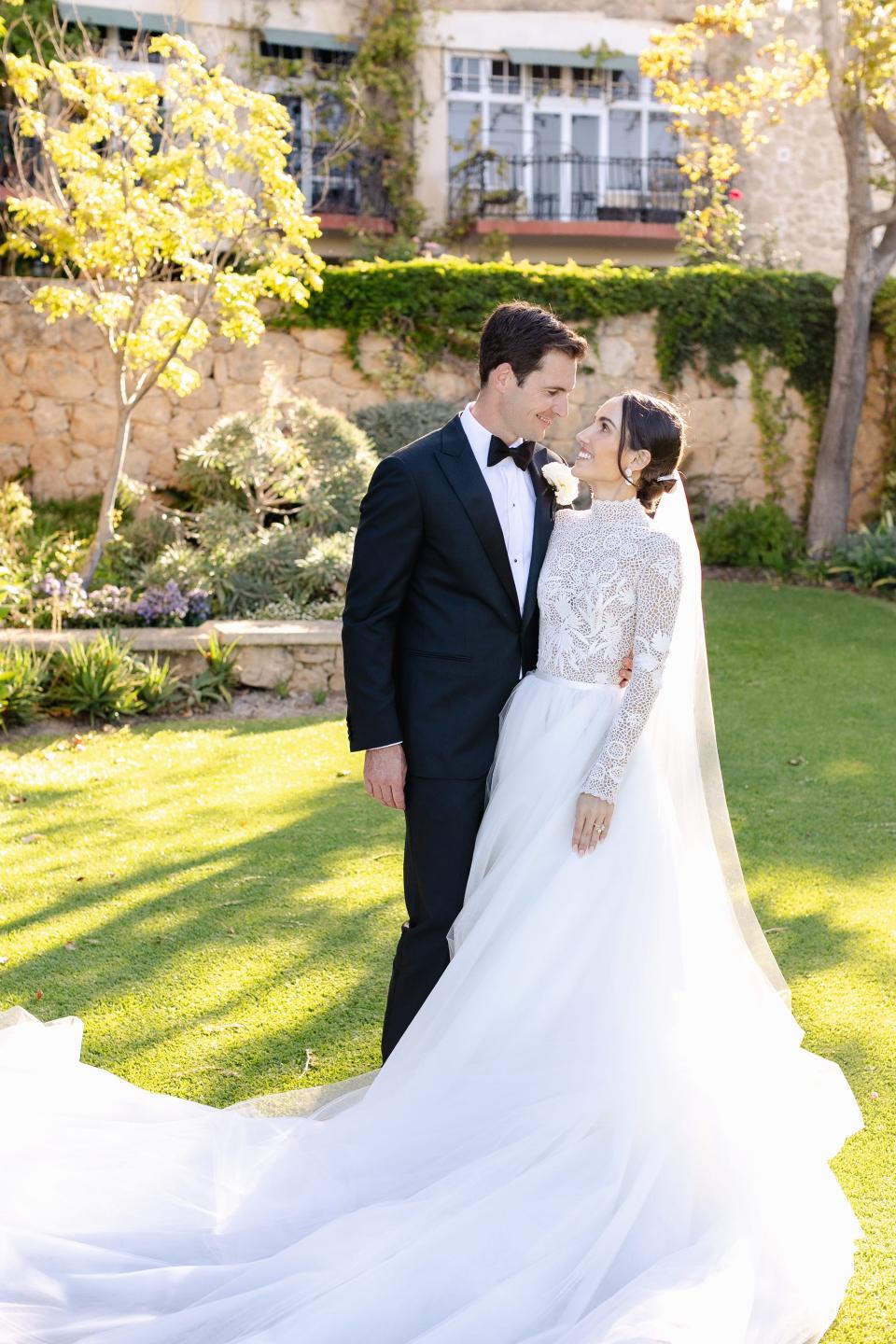 A bride and groom look at each other in their wedding attire.