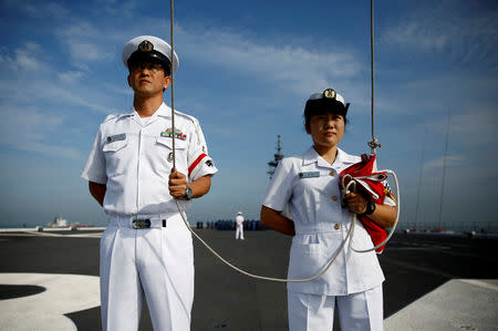 Male and female sailors prepare for a flag raising ceremony on the flight deck of Japanese helicopter carrier Kaga before its departure for naval drills in the Indian Ocean, Indonesia, September 22, 2018. Japan's navy struggles more to find recruits than the air force or army, as young people balk at the prospect of being cut off from social media networks on long deployments. REUTERS/Kim Kyung-Hoon