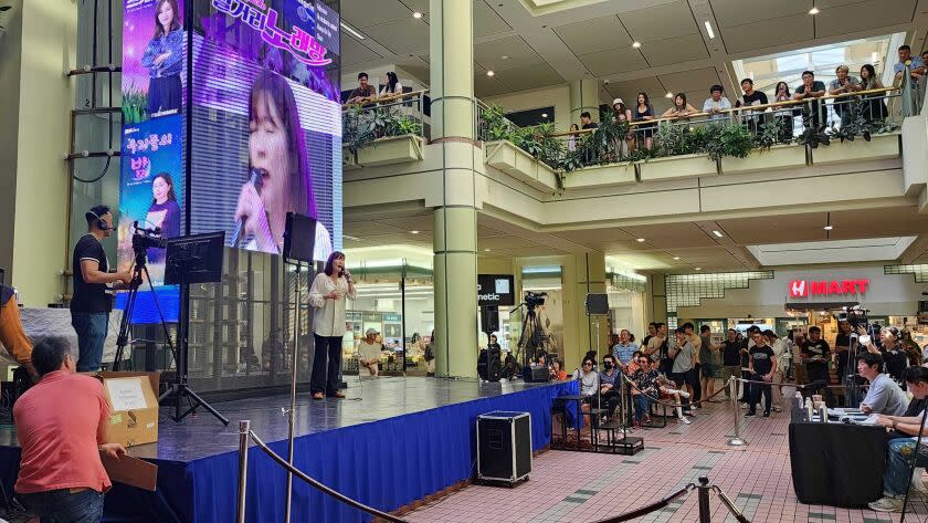 A woman performs at a karaoke competition in a mall