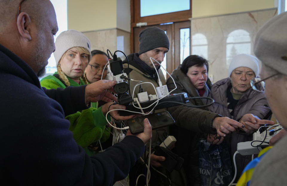 People charge their phones, try to connect to the internet and make phone calls, in central square in Kherson, Ukraine, Tuesday, Nov. 15, 2022. Waves of Russian airstrikes rocked Ukraine on Tuesday, with authorities immediately announcing emergency blackouts after attacks from east to west on energy and other facilities knocked out power and, in the capital, struck residential buildings. (AP Photo/Efrem Lukatsky)