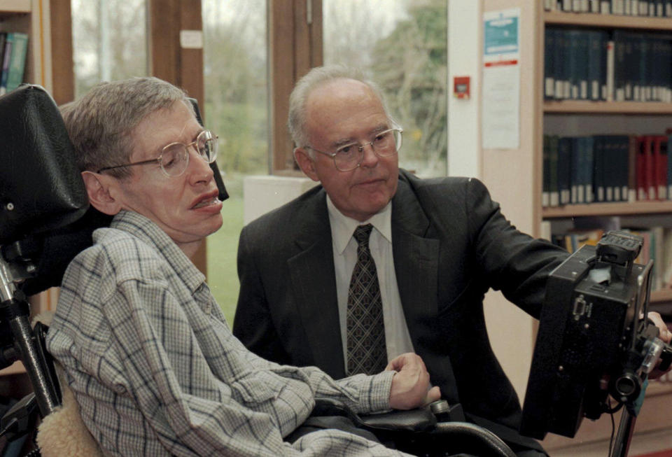 FILE Physicist Stephen Hawking, left, looks at a new custom-built computer designed especially for him with Dr. Gordon Moore of the Intel Corporation in the library of The Issac Newton Institute of Mathematics in Cambridge, England, Thursday, March 20, 1997. Moore, the Intel Corp. co-founder who set the breakneck pace of progress in the digital age with a simple 1965 prediction of how quickly engineers would boost the capacity of computer chips, has died. He was 94. Intel and the Gordon and Betty Moore Foundation say Moore died Friday, March 24, 2023 at his home in Hawaii. (AP Photo, File)
