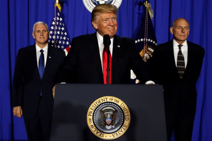 President Donald Trump center, flanked by Vice President Mike Pence and Homeland Security Secretary John Kelly, takes the stage to deliver remarks at Homeland Security headquarters. (Photo: Jonathan Ernst/Reuters)