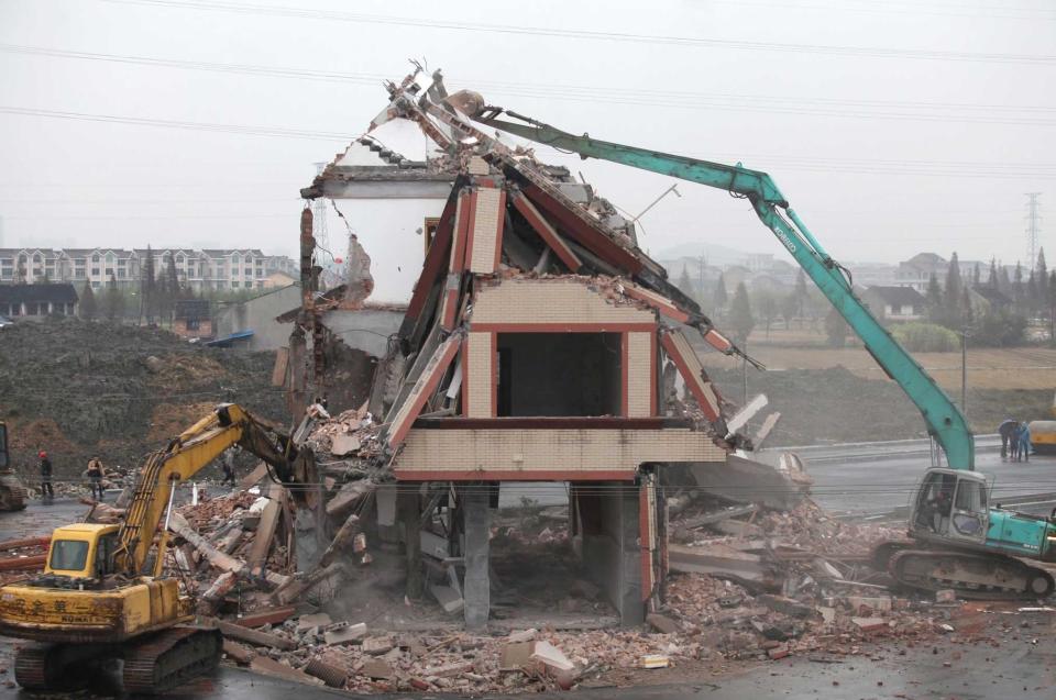 The house is finally demolished, despite the road already built around it (Rex)