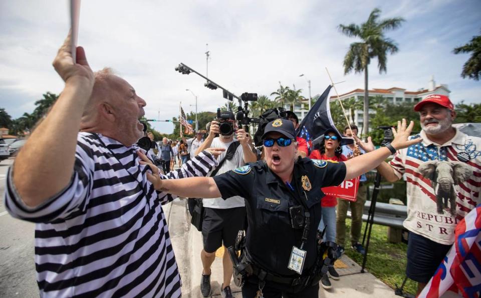 Anti-Trumper Domenic Santana, left, and a pro-Trump supporter, right, are separated by a police officer near the entrance of Trump National Doral Miami on Monday, June 12, 2023, in Doral, Fla.