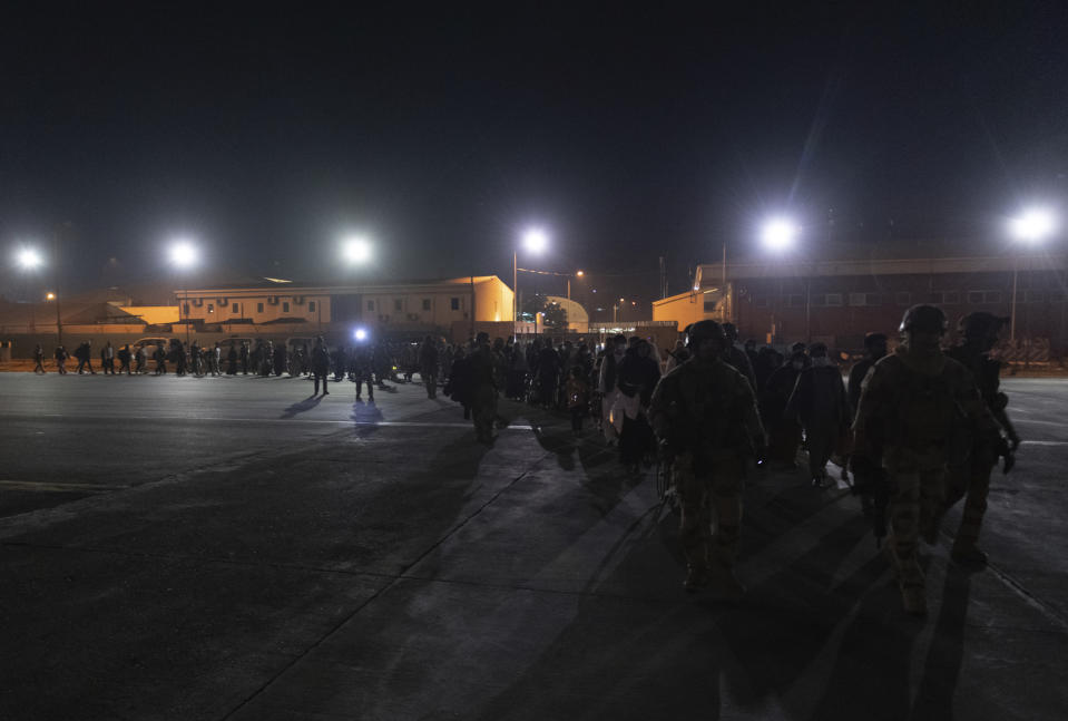 This photo provided Tuesday Aug.24, 2021 by the French Army shows French soldiers escorting people at Kabul airport, Afghanistan, Saturday Aug. 21, 2021. France has evacuated over 1,000 Afghans from Kabul over the past week, including a large majority of Afghans who worked with the French government or French groups in the country. (Etat-Major des Armees via AP)