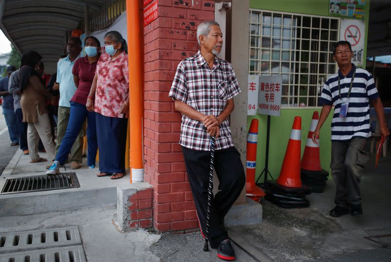 People wait outside a polling station before the polling process for a state election to begin at Selayang
