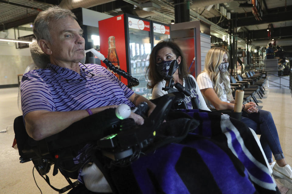 Jim Hilliard, Tamara Hilliard and Kat Minnerly watch the Colorado Rockies play against the Texas Rangers in an exhibition baseball game Tuesday, July 21, 2020 in Arlington, Texas. The Hilliards are the parents of Rockies left fielder Sam Hilliard and Minnerly is his fiancee. (AP Photo/Richard W. Rodriguez)