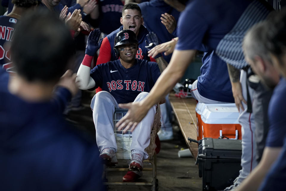 Boston Red Sox's Rafael Devers celebrates in the dugout after a grand slam home run against the Houston Astros during the second inning in Game 2 of baseball's American League Championship Series Saturday, Oct. 16, 2021, in Houston. (AP Photo/David J. Phillip)