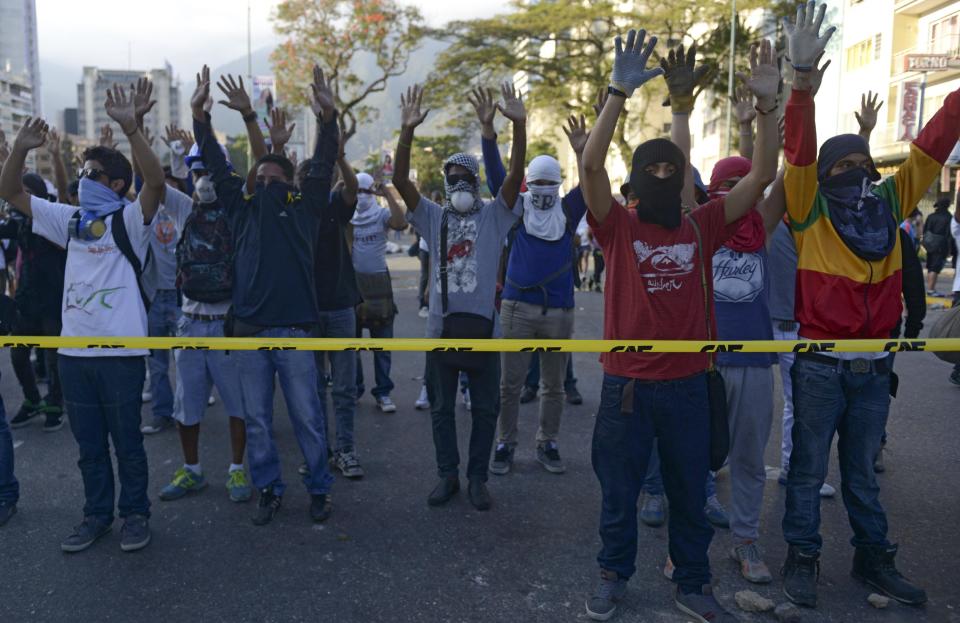 Varios manifestantes levantan las manos en señal de protesta contra el Gobierno de Venezuela, el lunes 24 de febrero en Caracas