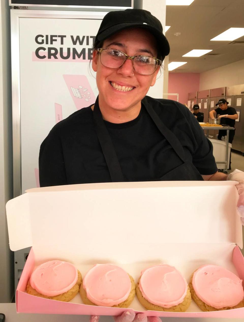 New Crumbl Cookies employee Heather Silva show off a freshly baked batch of pink sugar cookies at the chain’s new Paso Robles store, which opens Friday, March 31, 2023.