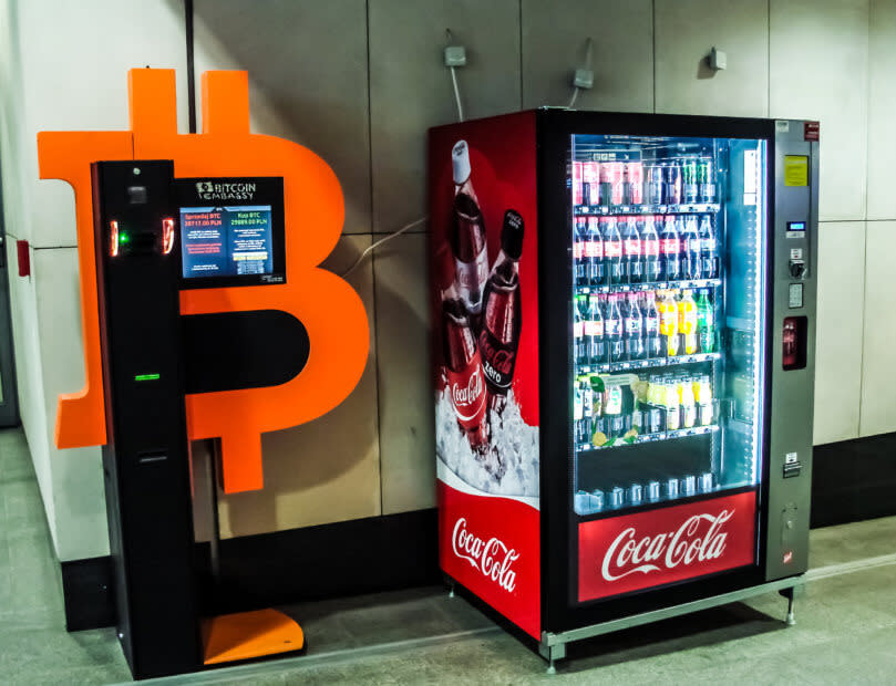 Ein Bitcoin-Automat steht neben einem Coca-Cola-Automat