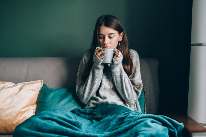 A woman sipping from a mug in bed