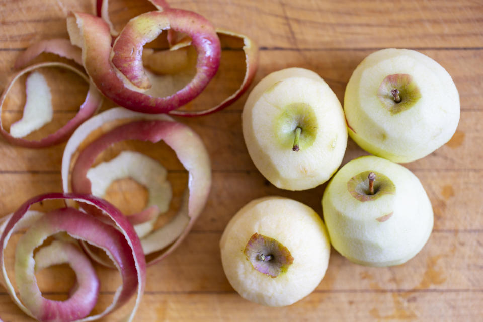 Geschälte und ungeschälte Äpfel auf einem Brett