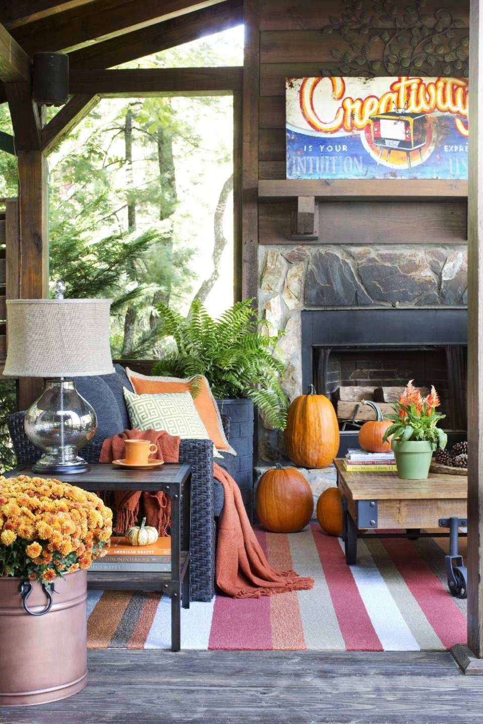 In this undated photo provided by Brian Patrick Flynn and Hayneedle.com, to ensure the outdoor living space of his mountain house stays warm and welcoming during the colder months, designer Brian Patrick Flynn chose woven blend upholstery for his seating, a wool and acrylic blend indoor-outdoor area rug, and throw pillows and blankets to keep guests feeling cozy. The wood burning fireplace is energy efficient and will still keep the area warm should electricity be lost during ice storms or snow storms. (AP Photo/Brian Patrick Flynn, Hayneedle.com)