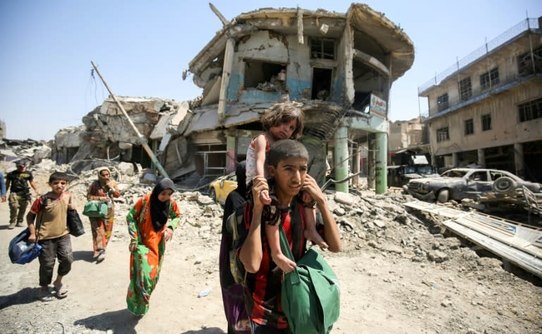 An Iraqi boy carries a girl on his back as they flee the Old City of Mosul on July 5, 2017