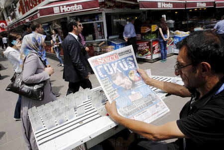 A lottery ticket vendor reads a Turkish newspaper published with an headline reads "downfall" and a portrait of Turkey's President Tayyip Erdogan in Ankara, Turkey, June 8, 2015. REUTERS/Umit Bektas