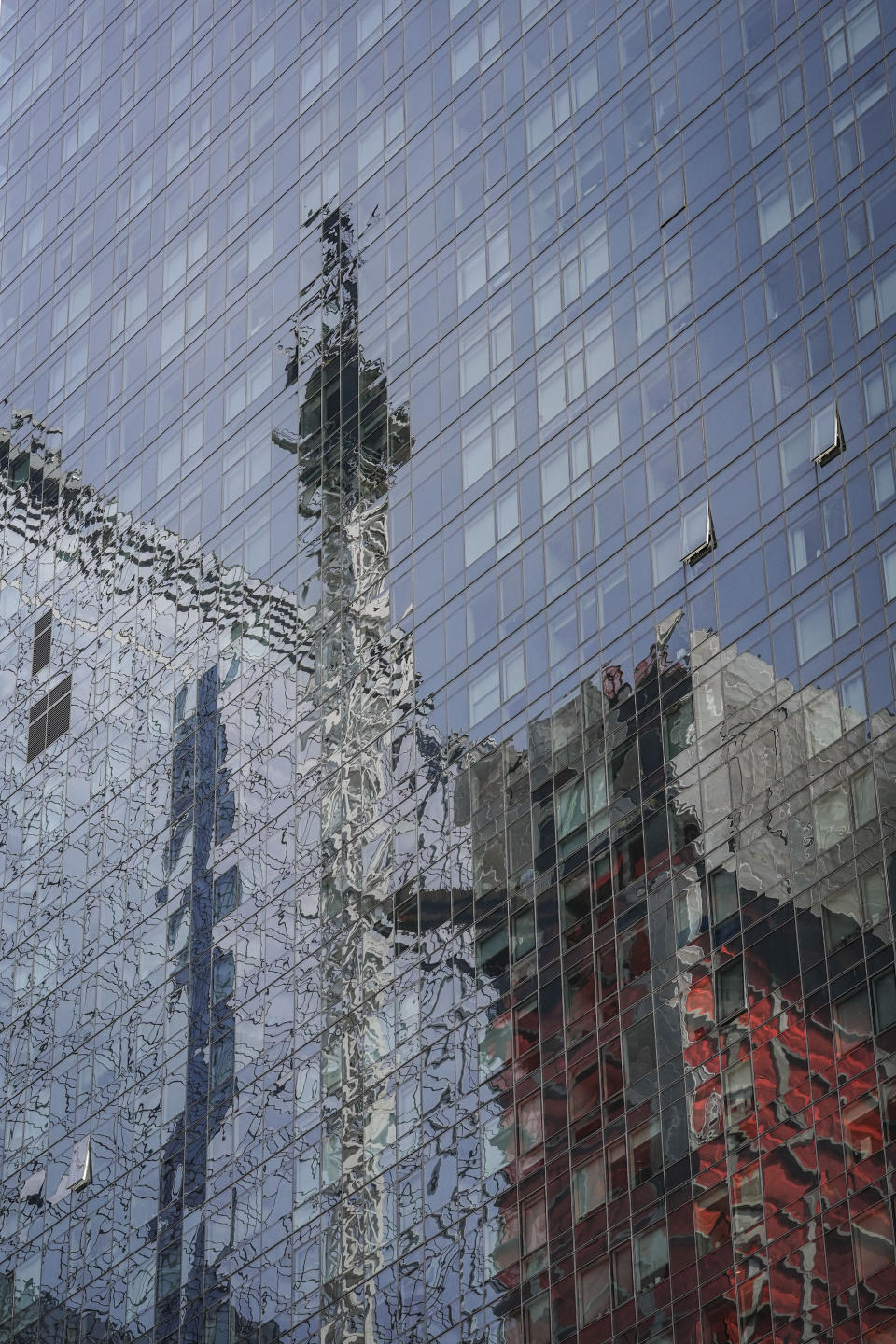 A glass paneled building reflects a hi-rise construction site crane, center, in the aftermath of a fire yesterday, that sent its extension arm plummeting to the street, Thursday July 27, 2023, in New York. (AP Photo/Bebeto Matthews)